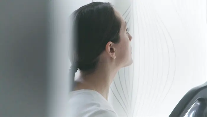 Una mujer mirando unas cortinas blancas.