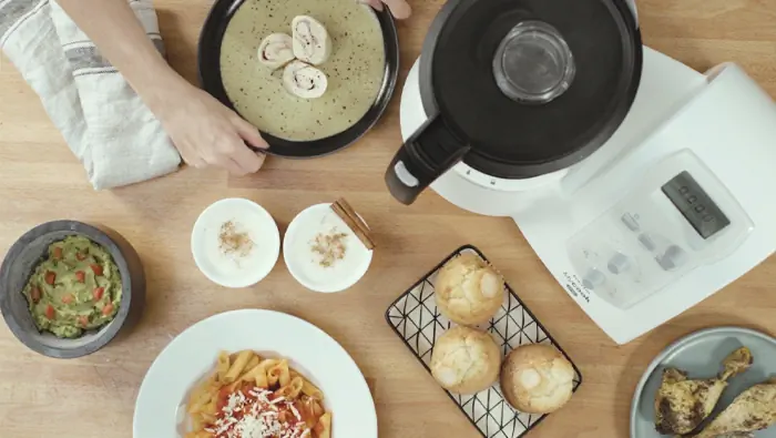 Una persona prepara comida en la cocina con un procesador de alimentos.