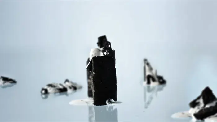 Composicion surrealista con conjunto de solidos negros en una superficie blanca.