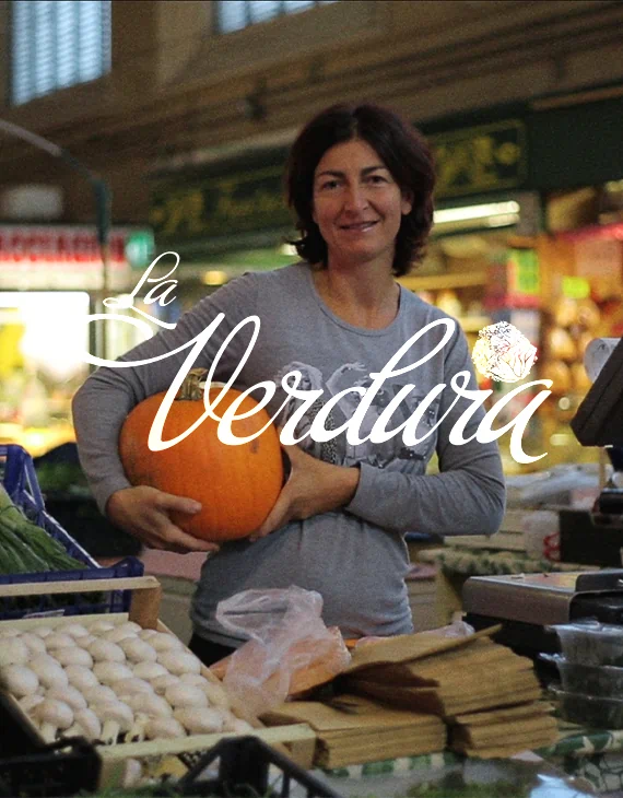 Vendedora en un puesto del mercado sujetando una calabaza de grande tamaño.