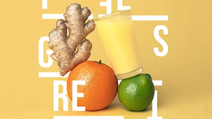 Una naranja, una lima, un jengibre y un vasito de zumo amarillo en fondo amarillo con letras blanca alrededor.